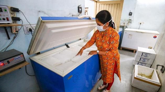A medic checks the temperature of ice packs in a deep freezer at a Covid-19 vaccine storage facility in Ahmedabad.(PTI)