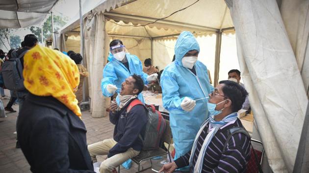 Healthcare workers in PPE coveralls collect swab samples for Covid-19 test at Anand Vihar Bus Terminal in New Delhi, on Saturday.(Sanchit Khanna/HT Photo)