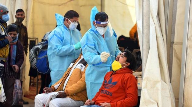 A health worker collects a swab sample from travellers for coronavirus testing at Anand Vihar Bus Terminal in New Delhi.(Raj K Raj/HT Photo)