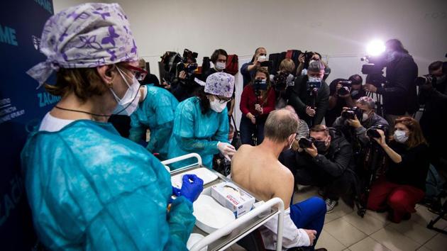 A man sits on a chair in front of media as he receives the Covid-19 vaccination on December 26 at the faculty hospital in Nitra, western Slovakia. Other nations are prioritising doctors, nurses and others on the front lines of fighting the virus. (Vladimir Simicek / AFP)
