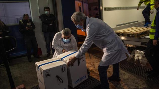 Medical workers carry the first shipment of Pfizer-BioNTech vaccines, at the premises of a pharmaceutical warehouse in Athens, Greece on December 26. The jab is a glimmer of hope for a continent still battling the pandemic in earnest, with infection rates again on the rise, lockdowns imposed and Christmas and New Year plans left in tatters for many. (Angeloz Tzortinis / AFP)