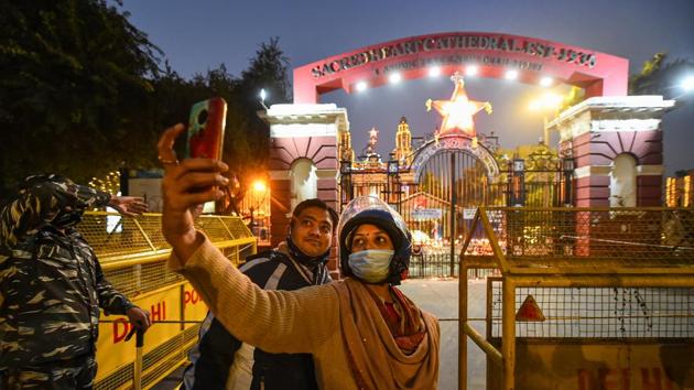 People take pictures near the closed gate of Sacred Heart Cathedral Church on the eve of Christmas, in New Delhi. In the wake of the Covid-19 pandemic, churches in Delhi will have low key Christmas celebrations this year with limited attendance for the mass and prohibition of entry of visitors. (PTI) People take pictures near the closed gate of Sacred Heart Cathedral Church on the eve of Christmas, in New Delhi. In the wake of the Covid-19 pandemic, churches in Delhi will have low key Christmas celebrations this year with limited attendance for the mass and prohibition of entry of visitors. (PTI)