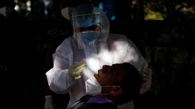 A health care worker wearing personal protective equipment collects a swab sample from a Border Security Force soldier, Gandhinagar, December 29, 2020(REUTERS)