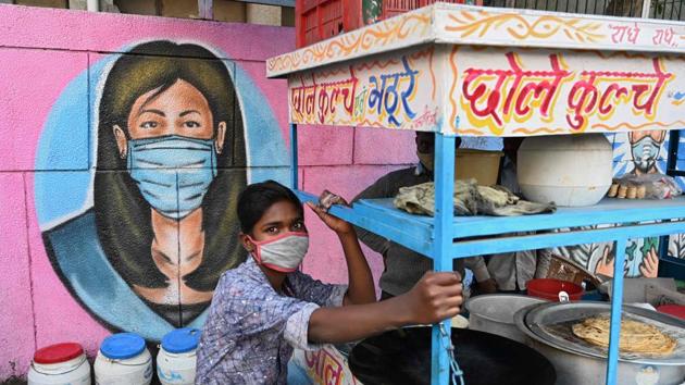 A vendor waits for customers at their roadside eatery stall in front of a mural representing a frontline worker, in New Delhi on December 27. The health ministry, meanwhile, said on December 28 that India’s recovery rate has increased to 95.83%. (Sajjad Hussain / AFP) A vendor waits for customers at their roadside eatery stall in front of a mural representing a frontline worker, in New Delhi on December 27. The health ministry, meanwhile, said on December 28 that India’s recovery rate has increased to 95.83%. (Sajjad Hussain / AFP)