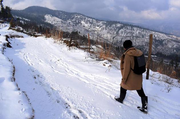 A man walks across a snow-bound stretch at Jarai village in Kotkhai town of Himachal Pradesh. The minimum and maximum temperatures in the hill state have seen a dip since the latest round of snowfall on Tuesday.(Deepak Sansta/HT)