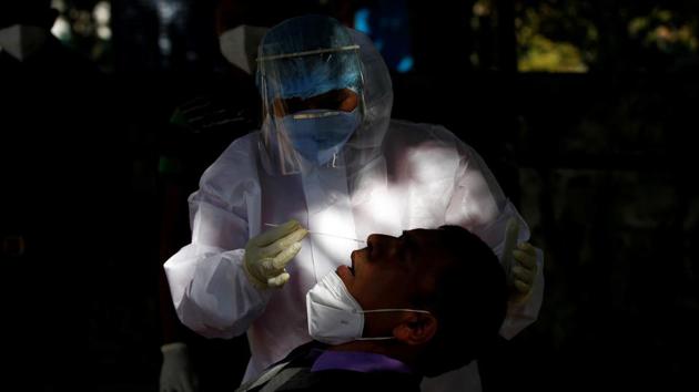 A healthcare worker wearing personal protective equipment (PPE) collects a swab sample from a Border Security Force (BSF) soldier during a rapid antigen testing campaign for the coronavirus disease (Covid-19), in Gandhinagar.(REUTERS)