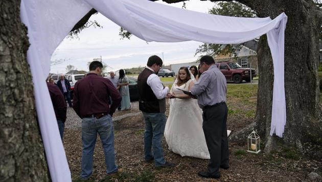Emily and Taylor Pascale exchange wedding vows outside the home of Taylor's parents, in Grand Lake, La., which was heavily damaged from Hurricanes Laura and Delta.(AP) Emily and Taylor Pascale exchange wedding vows outside the home of Taylor's parents, in Grand Lake, La., which was heavily damaged from Hurricanes Laura and Delta.(AP)