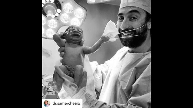 The image shows a newborn baby pulling a doctor’s mask. (Instagram/@dr.samercheaib) The image shows a newborn baby pulling a doctor’s mask. (Instagram/@dr.samercheaib)