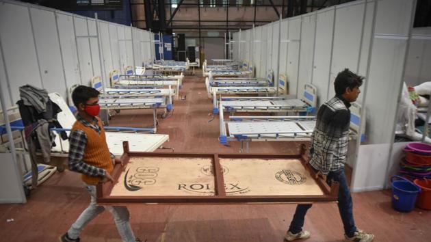 Workers dismantle beds at the CWG Village Covid centre. The centre may now be used for vaccination drive.(Sanchit Khanna/HT PHOTO) Workers dismantle beds at the CWG Village Covid centre. The centre may now be used for vaccination drive.(Sanchit Khanna/HT PHOTO)