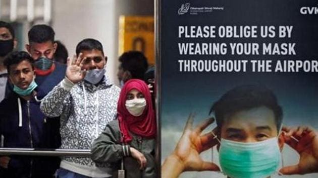 People wearing protective face masks wait for passengers to arrive at Chhatrapati Shivaji Maharaj International Airport.(REUTERS)