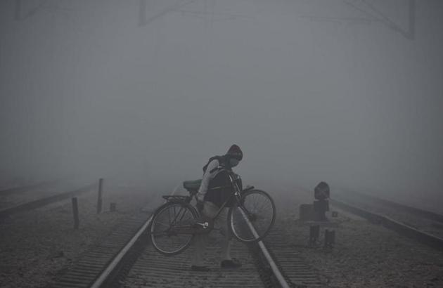 A cyclist crossing a railway track in Gurugram amid dense fog.(Parveen Kumar/HT)