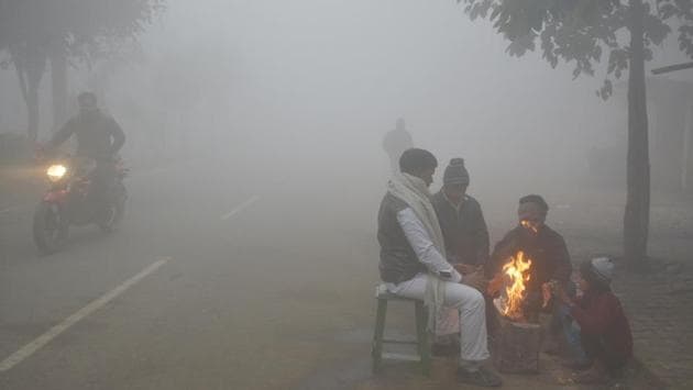People huddle around a bonfire on NH-9 to keep themselves warm amid a foggy morning in Dasna, Ghaziabad on January 1. Uplifted fog cover over Punjab and Haryana is also making it colder. The effect of La Niña, a global meteorological phenomenon, also contributed to the fall in temperatures over northwest India this year,” Kuldeep Shrivastava, head, regional weather forecasting centre, told HT. (Sakib Ali / HT Photo)