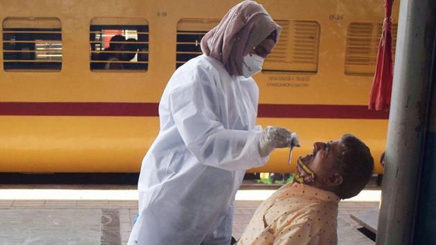 A health worker collects a sample from a train passenger for a Covid test.(ANI) A health worker collects a sample from a train passenger for a Covid test.(ANI)