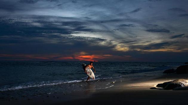A man is seen with a surfboard during the last sunset of the year at Lhoknga beach in Aceh province, Indonesia on December 31. (Chaideer Mahyuddin / AFP)