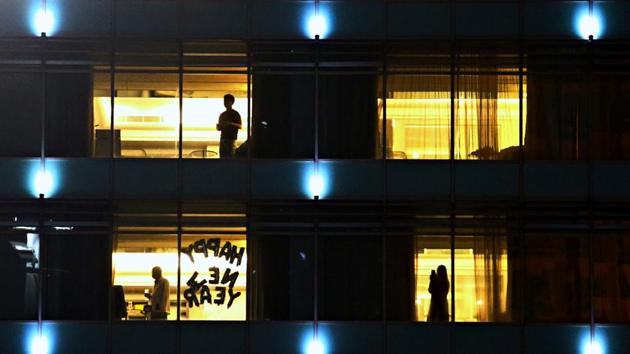 People stand at a hotel with a sign “Happy New Year” in one of its windows, during New Year's Eve amid the coronavirus disease (Covid-19) pandemic in Jakarta, Indonesia on December 31. (Ajeng Dinar Ulfiana / REUTERS)