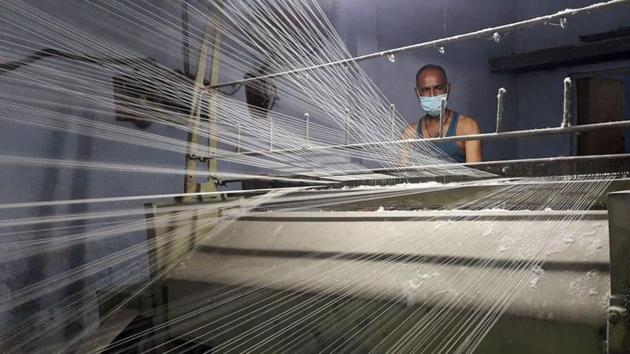 A worker wearing a protective face mask works on a loom in a textile factory, amidst the coronavirus disease (Covid-19) outbreak, in Meerut, India.(Reuters)