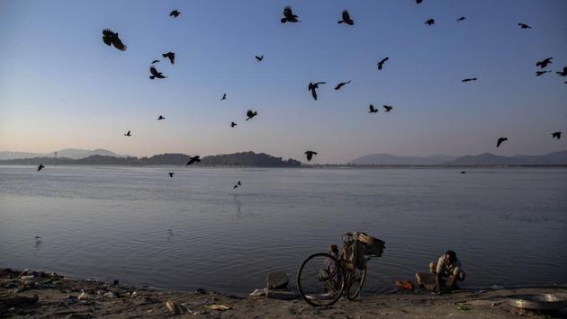 Crows fly over fish sellers cleaning their containers by the bank of Brahmaputra river in Guwahati on January 1. There are total 250,183 active cases of the coronavirus disease at present and the death toll has risen to 149,218 with the case fatality rate at 1.45%. The 224 fatalities added in the previous 24 hours were lower than the toll a day prior at 256. (Anupam Nath / AP)