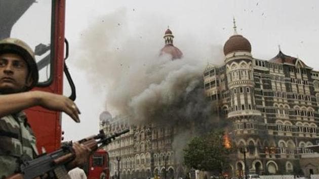 Indian soldier takes cover as the Taj Mahal hotel burns during gun battle between Indian military and militants inside the hotel in Mumbai, India.(AP file photo)