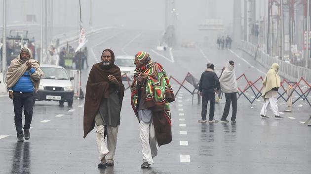 Farmers walk through rain during a protest against the new farm laws, at Ghazipur border near New Delhi on Sunday.(PTI Photo)