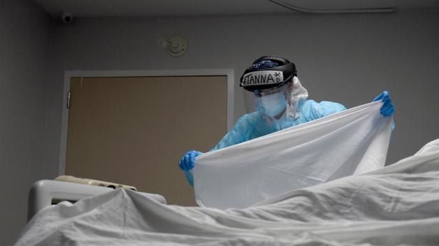 Health worker places a sheet over the body of a patient who died inside the coronavirus disease (Covid-19) unit at United Memorial Medical Center in California, US.(Reuters)