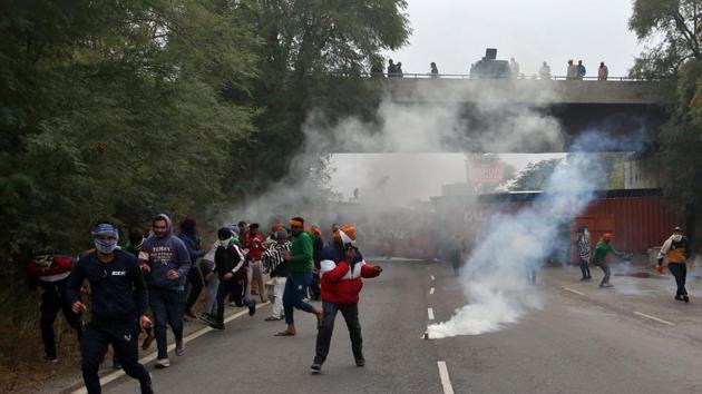Farmers protesting against newly passed agricultural reforms run away from tear gas fired by police on a national highway at Dharuhera, in the northern state of Haryana, India.(Reuters) Farmers protesting against newly passed agricultural reforms run away from tear gas fired by police on a national highway at Dharuhera, in the northern state of Haryana, India.(Reuters)