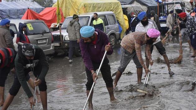 Demonstrators clearing a stretch of rainwater and mud on a rainy day at Singhu border during protests against new farm laws, near New Delhi, India, on Sunday.(Vipin Kumar/HT photo) Demonstrators clearing a stretch of rainwater and mud on a rainy day at Singhu border during protests against new farm laws, near New Delhi, India, on Sunday.(Vipin Kumar/HT photo)
