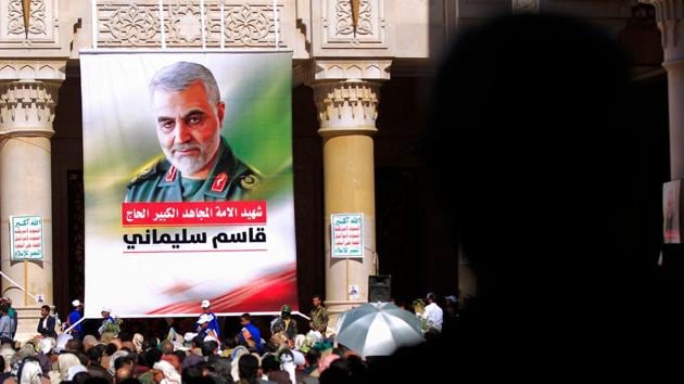 People stand beneath a portrait of slain Iranian Revolutionary Guards commander Qasem Soleimani during a vigil in the Yemeni capital of Sanaa on January 2, 2021, ahead of the first anniverary of his killing by a US drone-strike.(AFP Photo)