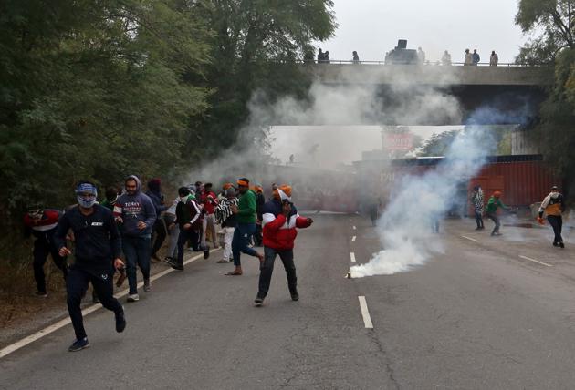 Farmers protesting against newly passed agricultural reforms run away from tear gas fired by police on a national highway at Dharuhera on Sunday.(REUTERS) Farmers protesting against newly passed agricultural reforms run away from tear gas fired by police on a national highway at Dharuhera on Sunday.(REUTERS)