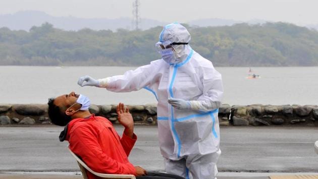 A health worker takes a swab sample from a person durning a free coronavirus disease screening camp at Sukhna Lake in Chandigarh.(Keshav Singh/HT Photo)