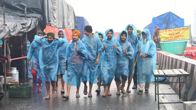 Demonstrators seen wearing rain suits to protect themselves from rain at Ghazipur border in New Delhi on Monday.(Raj K Raj/HT PHOTO)