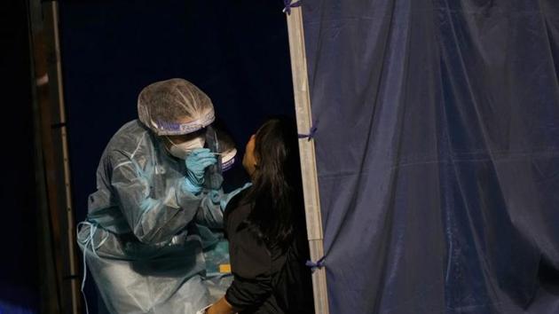A health worker collects a swab sample from a woman at a makeshift testing centre on a soccer field following the coronavirus disease outbreak in Hong Kong on December 8, 2020.(Reuters file photo)