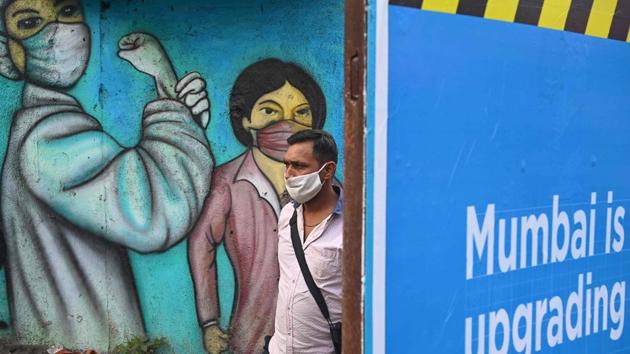 A commuter walks past a wall mural depicting Covid-19 frontline workers in Mumbai on January 5. The ratio of active cases compared to the total cases reported has now dropped to 2.5% against 26.33% recorded on September 17. (Indranil Mukherjee / AFP)