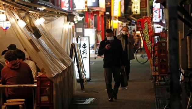 People wearing protective face masks walk past at a Japanese izakaya pub alley, amid Covid-19 outbreak, in Tokyo, Japan.(REUTERS) People wearing protective face masks walk past at a Japanese izakaya pub alley, amid Covid-19 outbreak, in Tokyo, Japan.(REUTERS)