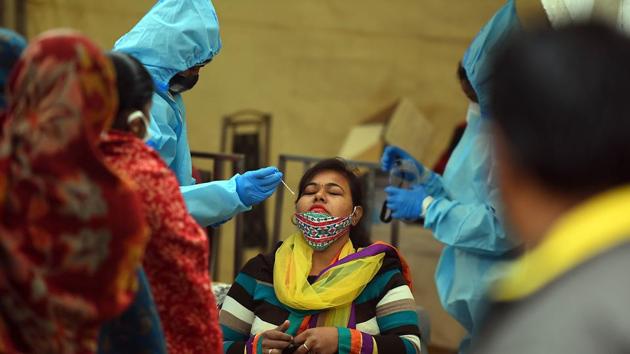 A health worker collects a swab sample for coronavirus testing at Anand Vihar Bus Terminal, in New Delhi.(Raj K Raj/HT PHOTO)