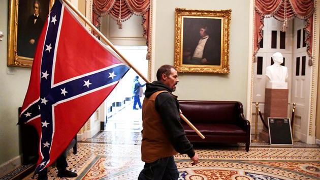 A protestor raising the Confederate flag inside the Capitol.