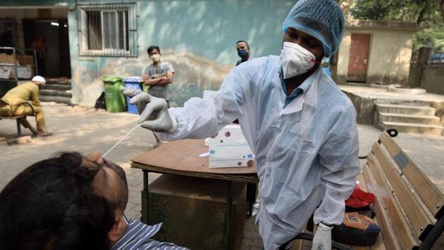 A BMC health care worker collects swab samples of residents at Kalanagar.(Satish Bate/HT Photo)