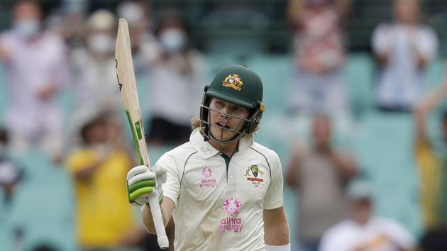 Australia's Will Pucovski waves his bat as he celebrates reaching 50 runs during play on day one of the third cricket test between India and Australia at the Sydney Cricket Ground, Sydney.(AP)