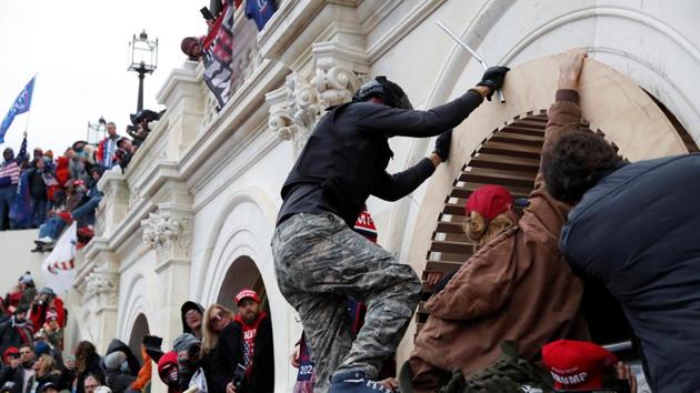 Pro-Trump protesters scale a wall as they storm the US Capitol Building, during clashes with Capitol police at a rally to contest the certification of the 2020 Presidential election results by the US Congress.(Reuters image) Pro-Trump protesters scale a wall as they storm the US Capitol Building, during clashes with Capitol police at a rally to contest the certification of the 2020 Presidential election results by the US Congress.(Reuters image)