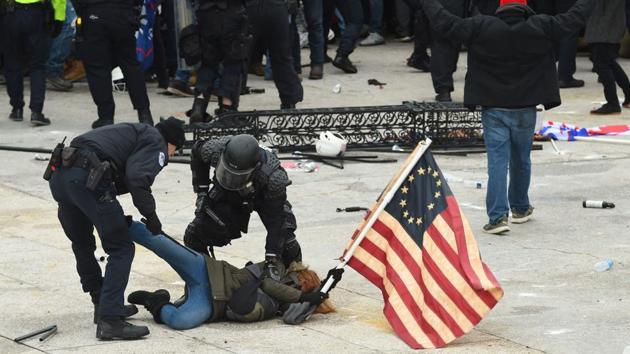 Police detain a person as supporters of US President Donald Trump protest outside the US Capitol on January 6. Washington’s mayor instituted an evening curfew in an attempt to contain the violence. (Roberto Schmidt / AFP) Police detain a person as supporters of US President Donald Trump protest outside the US Capitol on January 6. Washington’s mayor instituted an evening curfew in an attempt to contain the violence. (Roberto Schmidt / AFP)