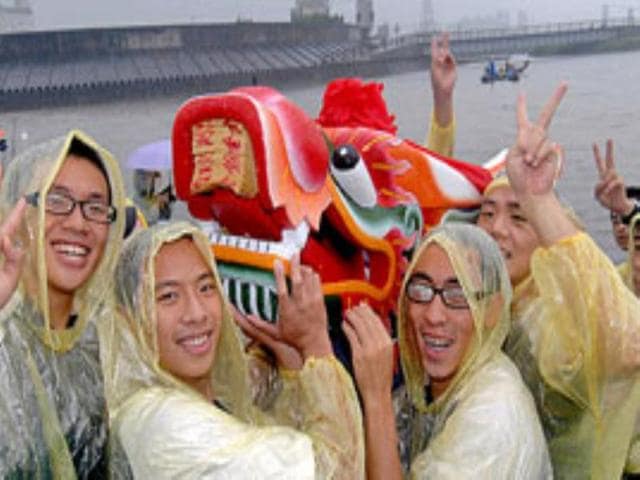 A few Taiwanese students pose holding an elaborately-carved dragon boat in Taipei.