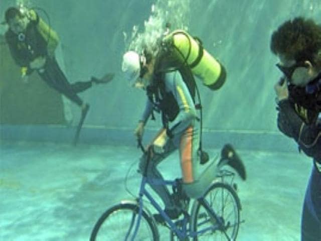 A participant rides a bicycle during an underwater sports meet at the Shengya Ocean World in Dalian.