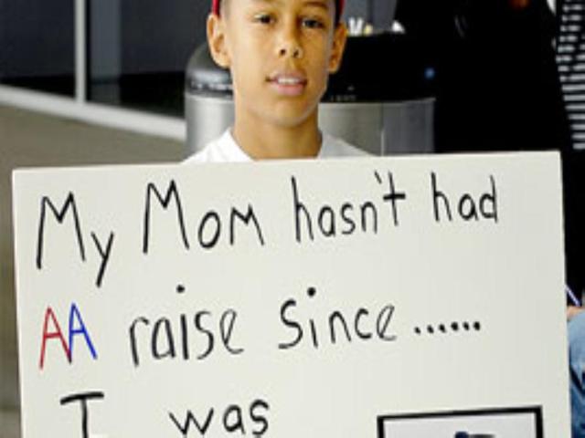 Elijah Hicks supports his mom Kim, who says she has not had a raise in 7 years, as the Transport Workers Union Local 513 members conduct an informational picket line to protest American Airlines executive bonuses.