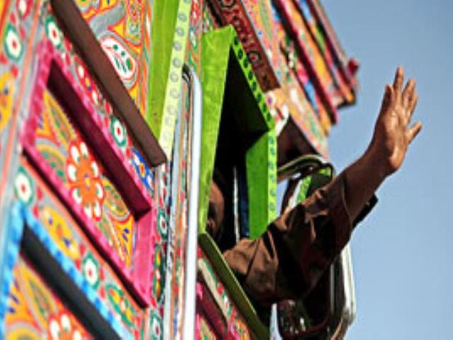 A truck driver waves goodbye as he drives the finished truck away from a workshop in Peshawar.