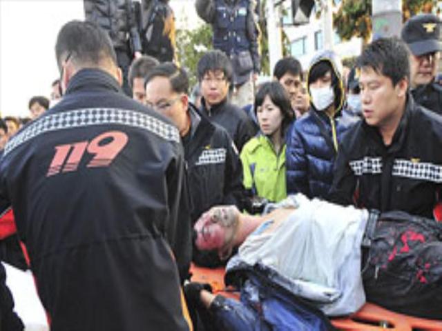 Rescue workers carry a wounded temporary employee of Hyundai Motor after he set fire to himself during a rally in front of Hyundai Motor's factory.