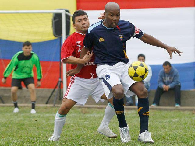 Peruvian prisoners, representing "Peru" (red) and "Ecuador" (blue), fight for the ball during the final match of their mock Copa America soccer tournament at Castro-Castro prison in Lima.