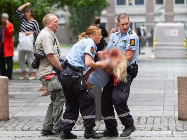Policemen evacuate an injured woman after a powerful explosion rocked central Oslo, Norway.