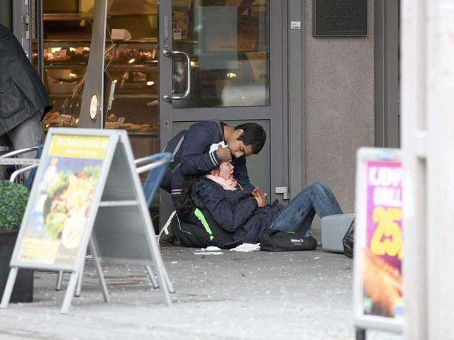 A man tends to a woman wounded after an explosion near government buildings in Oslo, Norway.