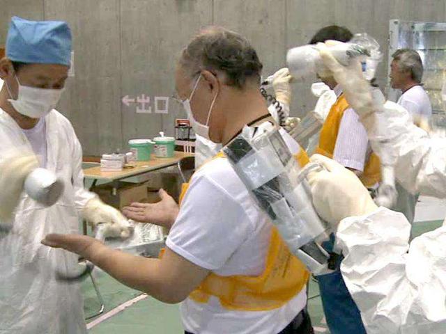IAEA Director General Yukiya Amano, center, is screened for radiation after his inspection tour at the crippled Fukushima Dai-ichi nuclear power plant at Okuma, northeastern Japan.