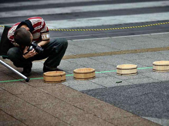 A man shoots wooden buckets placed on the ground before a promotional event to begin in Tokyo.