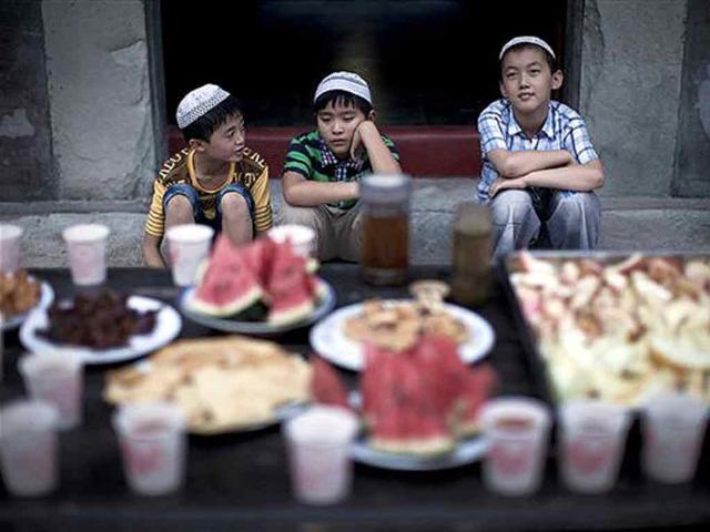 A Chinese Hui Muslim boys waits in front of food as they wait to break their fast on the first day of the Muslim holy month of Ramadan in Beijing, China.